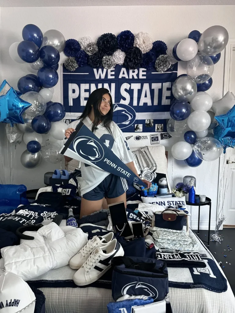 Student celebrating her Penn State commitment at a bed party, holding a Penn State pennant