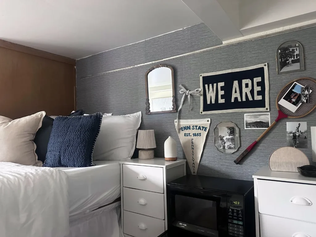 Finished Penn State dorm room with white bedding, a We Are pennant and a styled photo wall