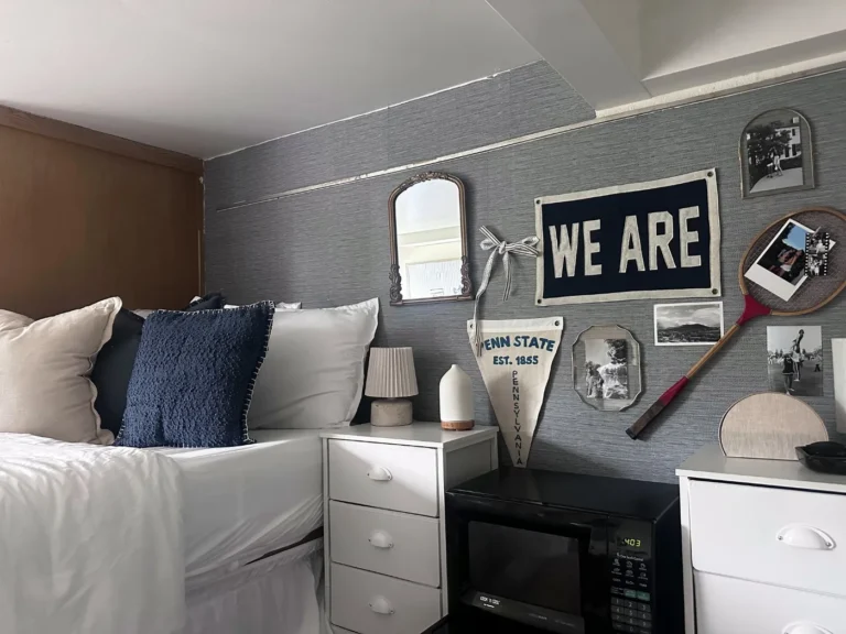 Finished Penn State dorm room with white bedding, a We Are pennant and a styled photo wall